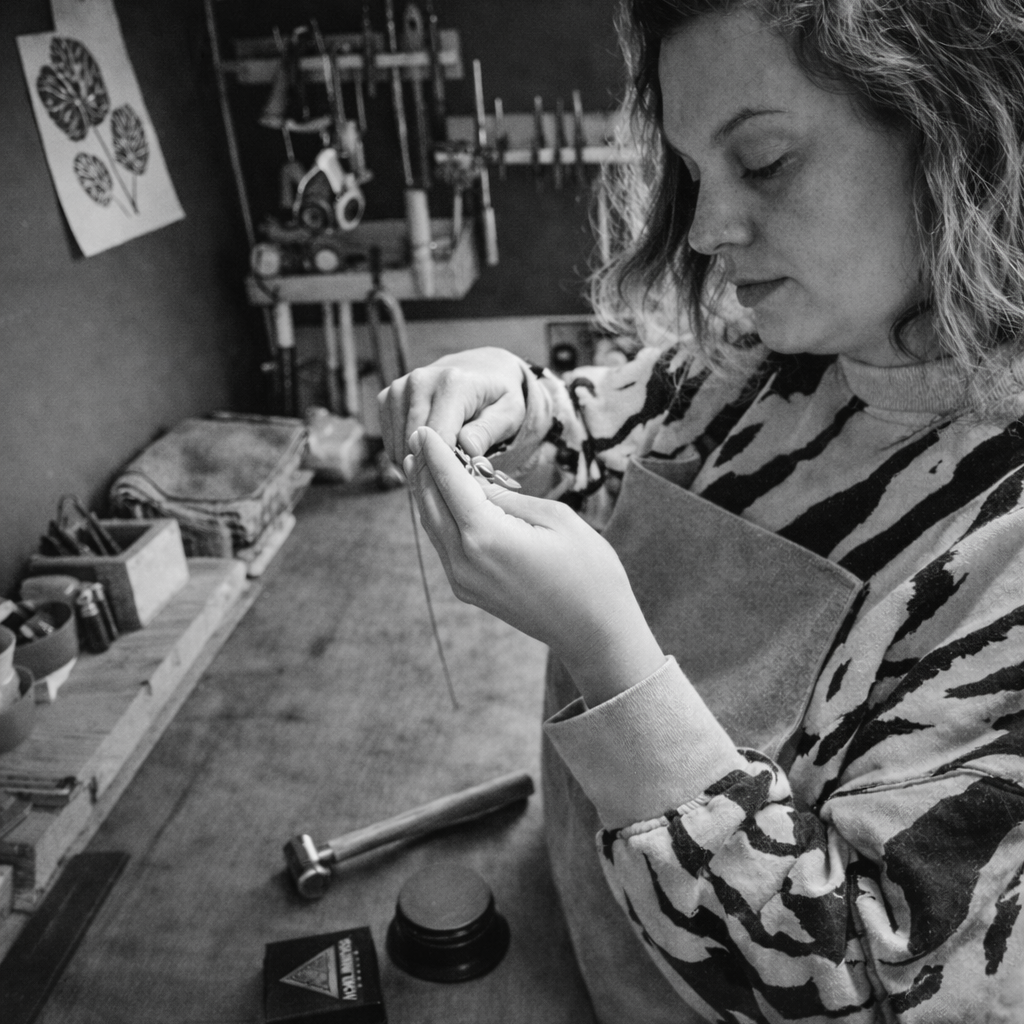 Black and white photo of a woman working in a studio with text 'Made by hand in my Cotswolds studio Rachel x'.