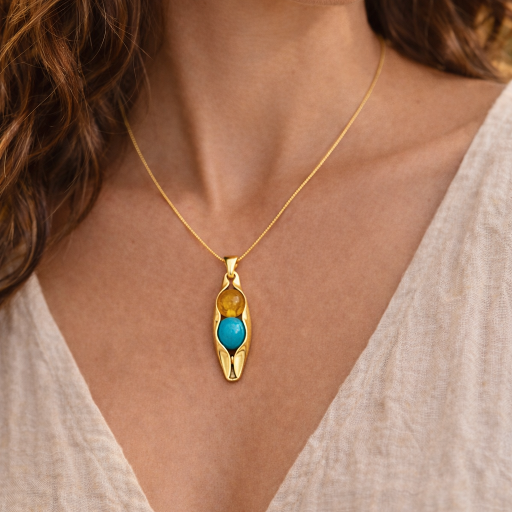 Woman wearing a gold necklace with a blue pendant
